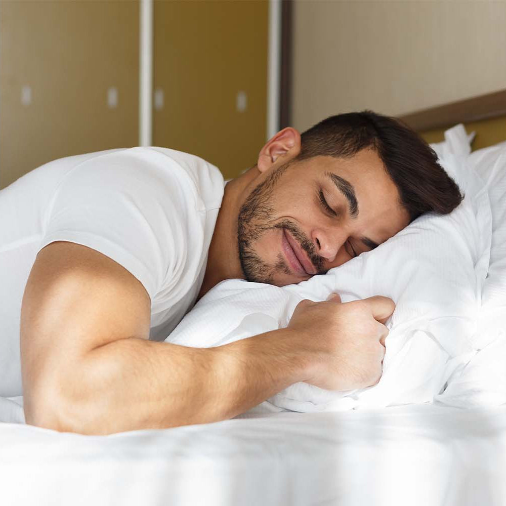 Man lying in bed while receiving a prostate massage.