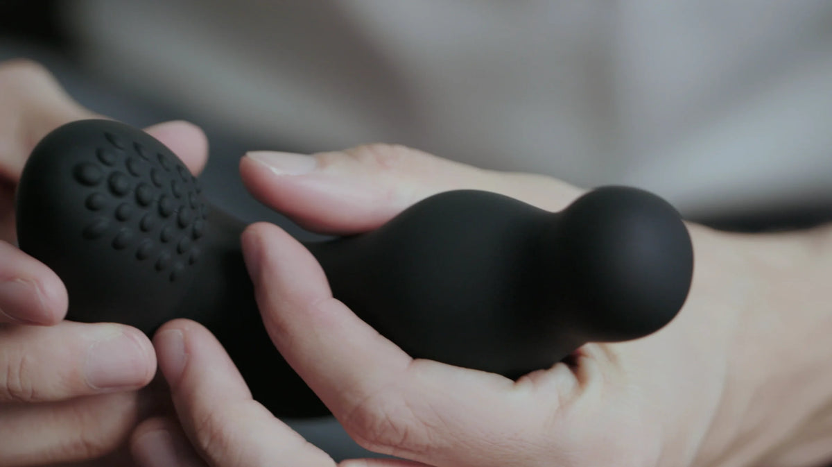 Thor butt plug held between two hands against a neutral background